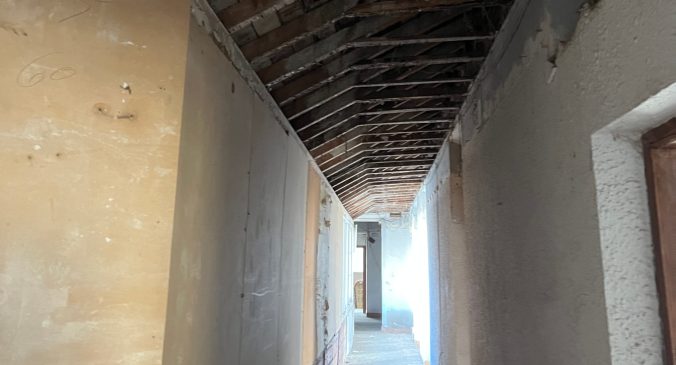 Pasillo de un edificio en proceso de rehabilitación con luz al fondo